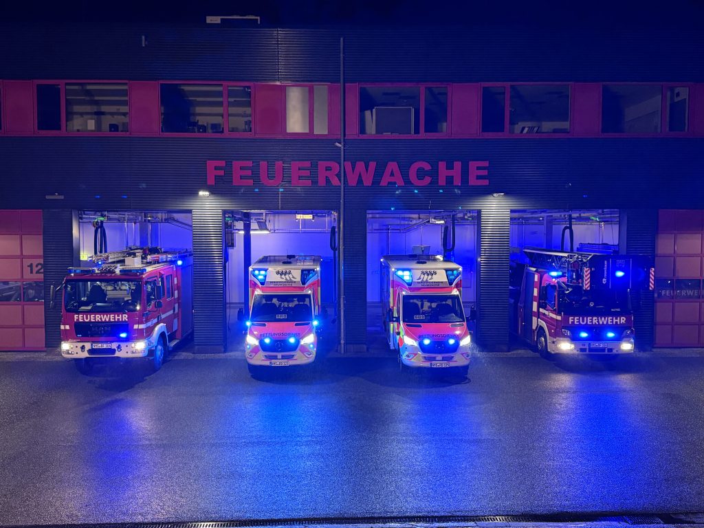 Löschfahrzeuge mit blinkendem Blaulicht vor der Feuerwache Neumünster